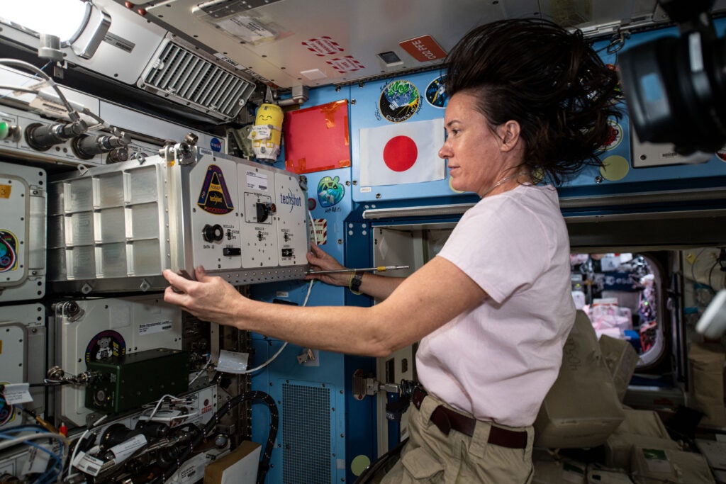 NASA astronaut Megan McArthur installs the "cassette" containing the UMAMI experiment inside the Kibo laboratory module aboard the International Space Station.