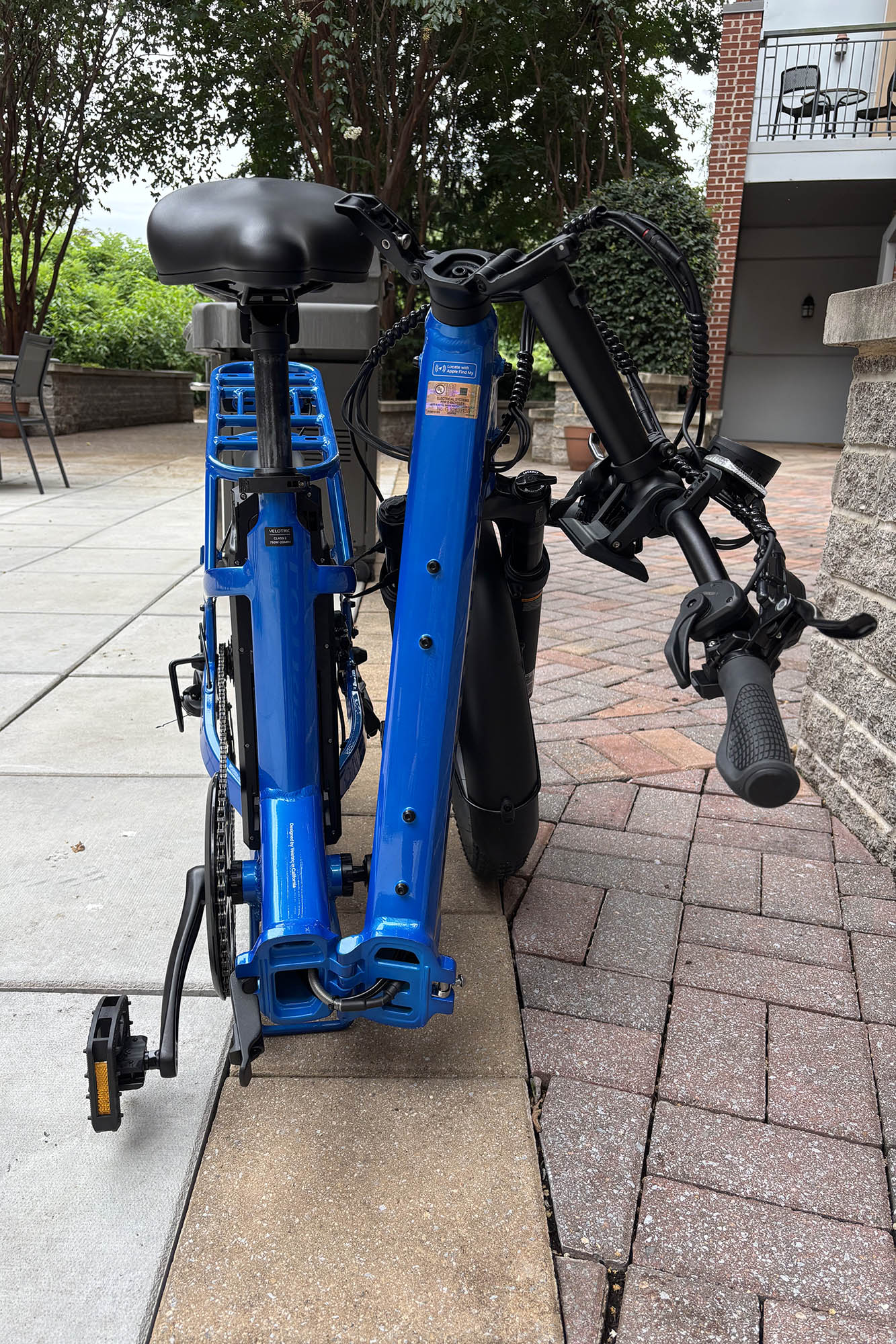 Gros plan frontal d'un pli vélotrique bleu 1 plus d'évike pliant complètement plié devant un mur de pierre gris