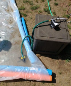 The pool at the end of a DIY slip and slide, with a water pump in position to recycle the water.