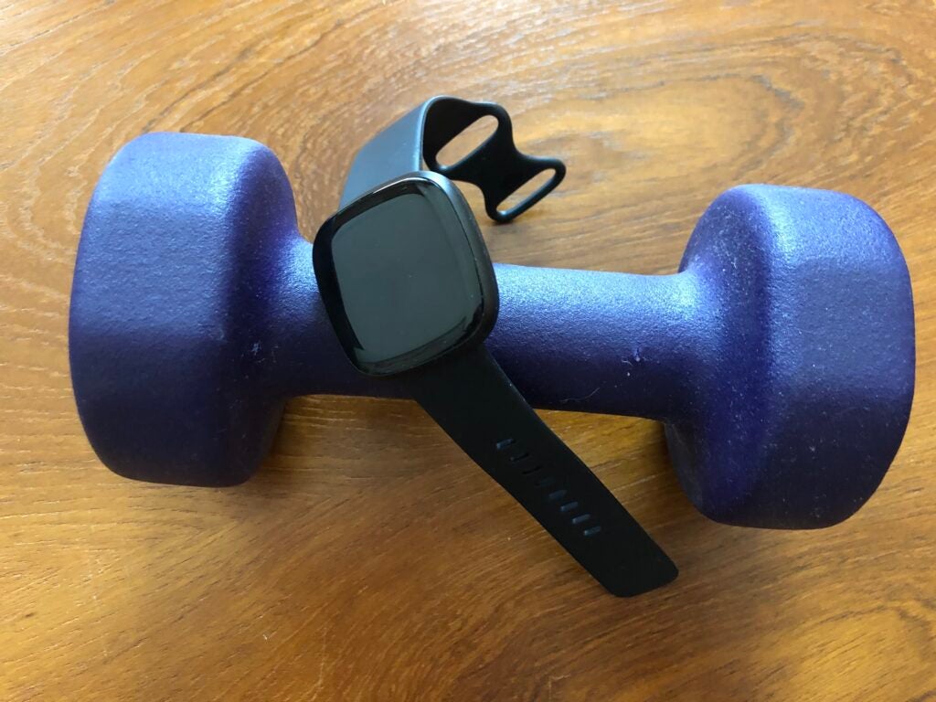 The Fitbit Versa 3 on a blue dumbbell