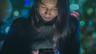 A woman looking at her phone screen at night while the screen illuminates her face