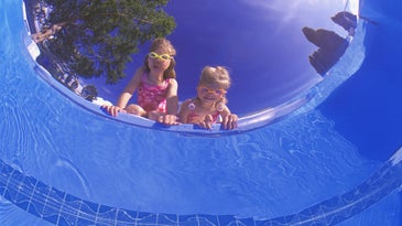 two kids stare down into a pool