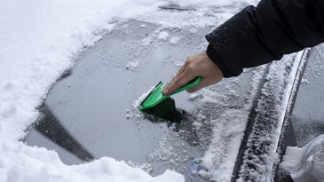 scraping ice and snow off a car windshield