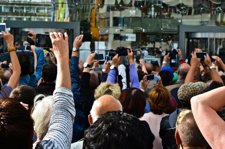 people holding up phones in crowd to take photographs