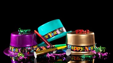 three colorful plastic hats that say happy new year on a black background with noisemakers and ribbons 