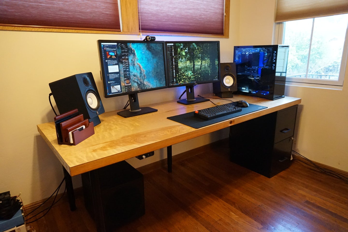 A DIY computer desk made out of a wooden door and some metal legs, with a dual-monitor computer and other devices on top of it.