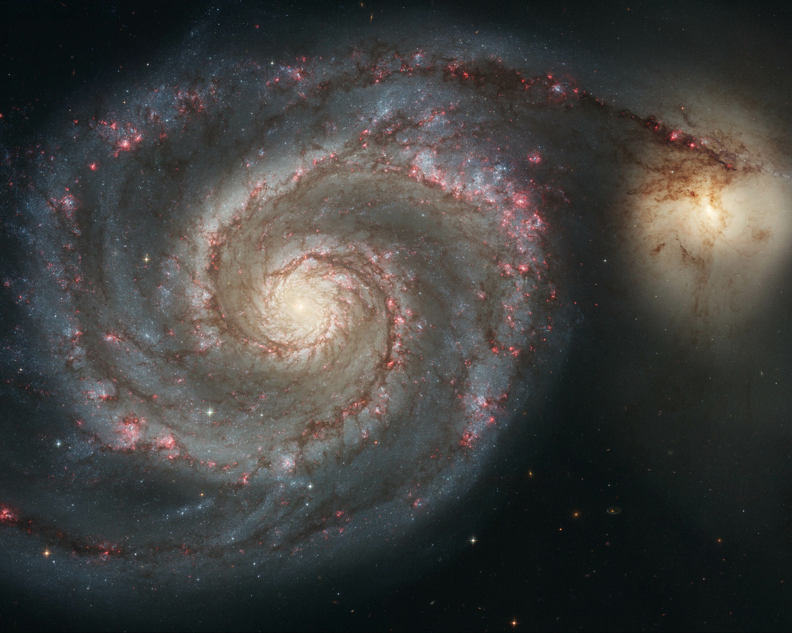 a large spiral galaxy next to a smaller ball of light in space