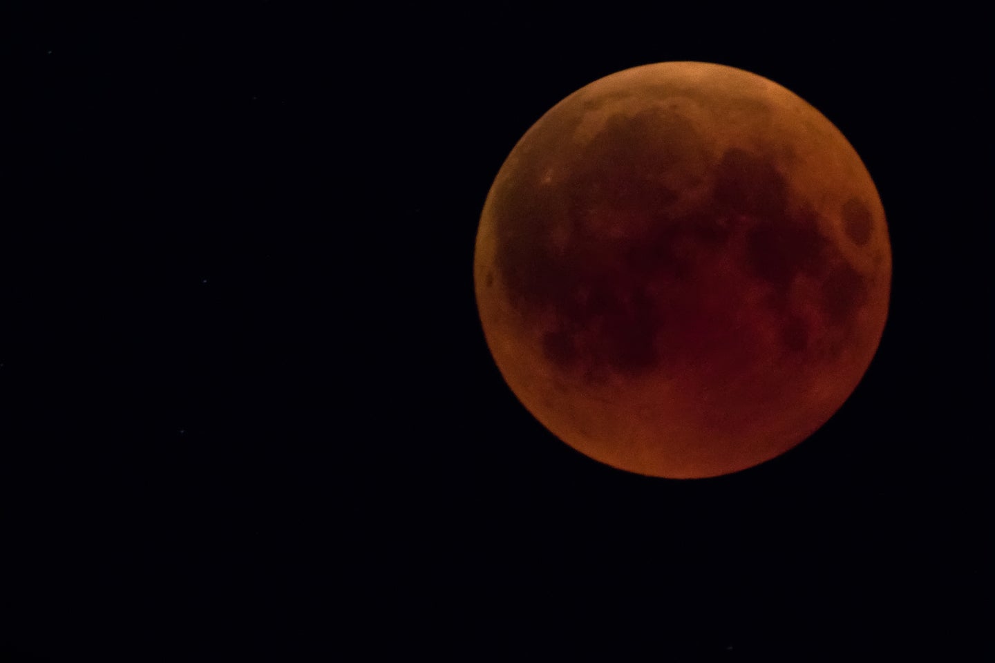 a moon with a red tint due to a lunar eclipse