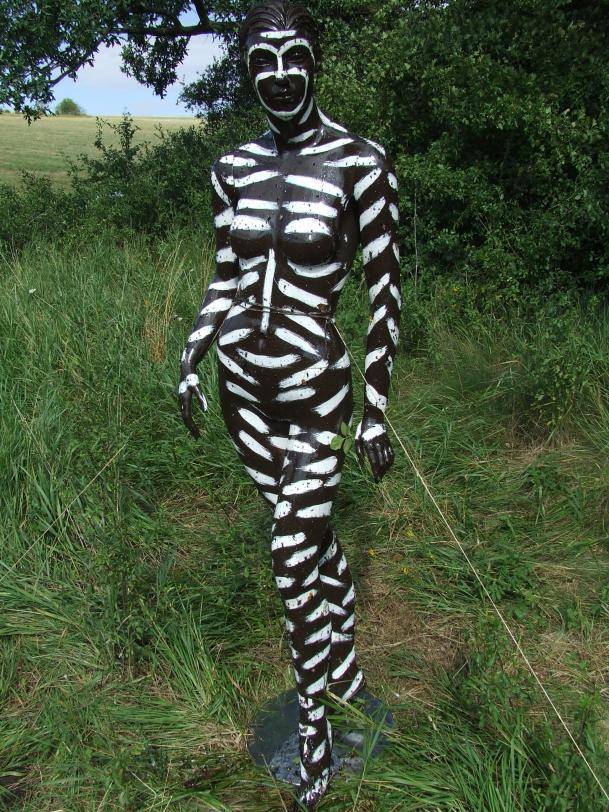 a mannequin painted with zebra stripes standing in a field
