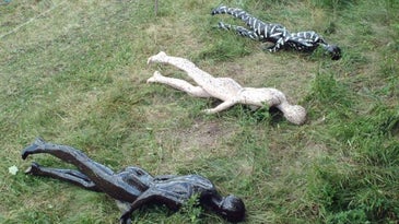 three mannequins lying face down in a field