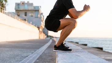 a man doing a squat on a beach