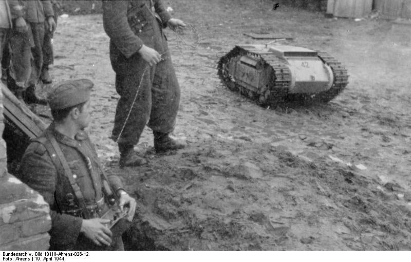 Goliath tracked mine on the field with soldiers in April 1944