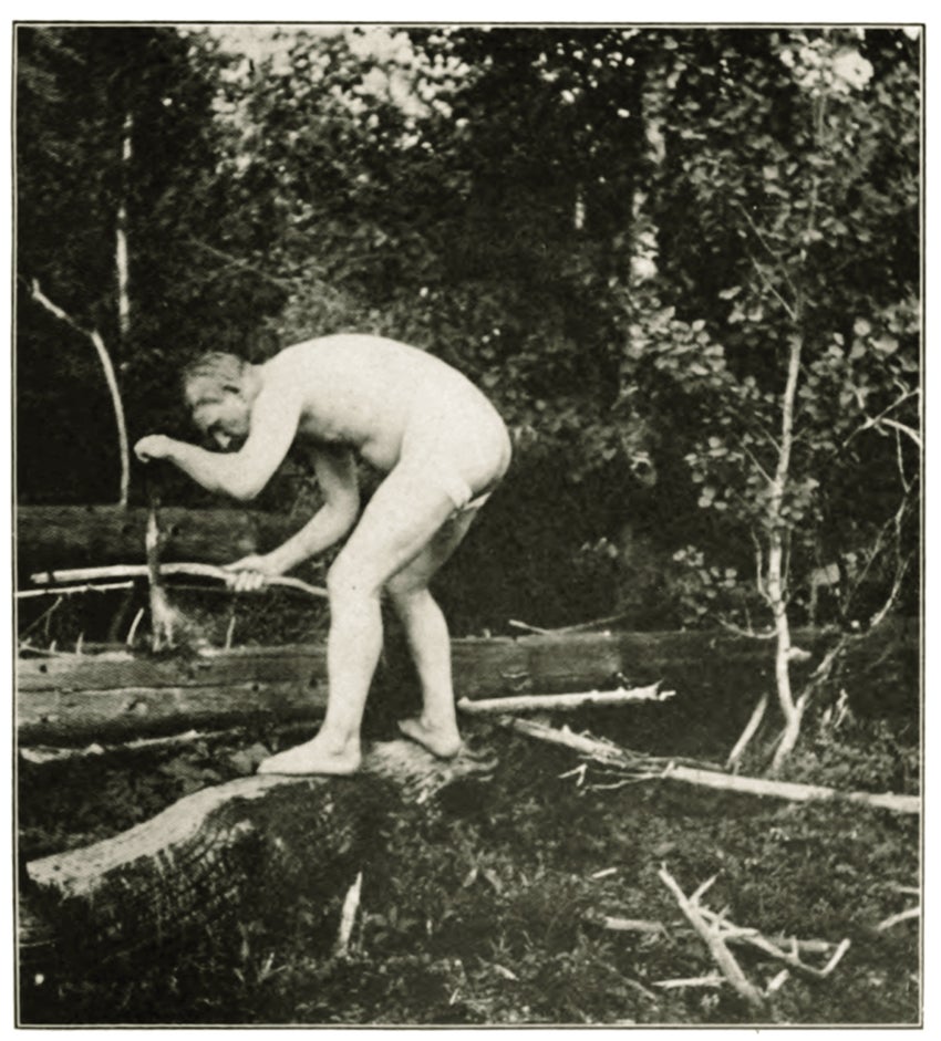 a man crouches naked in the woods in an old black and white photo
