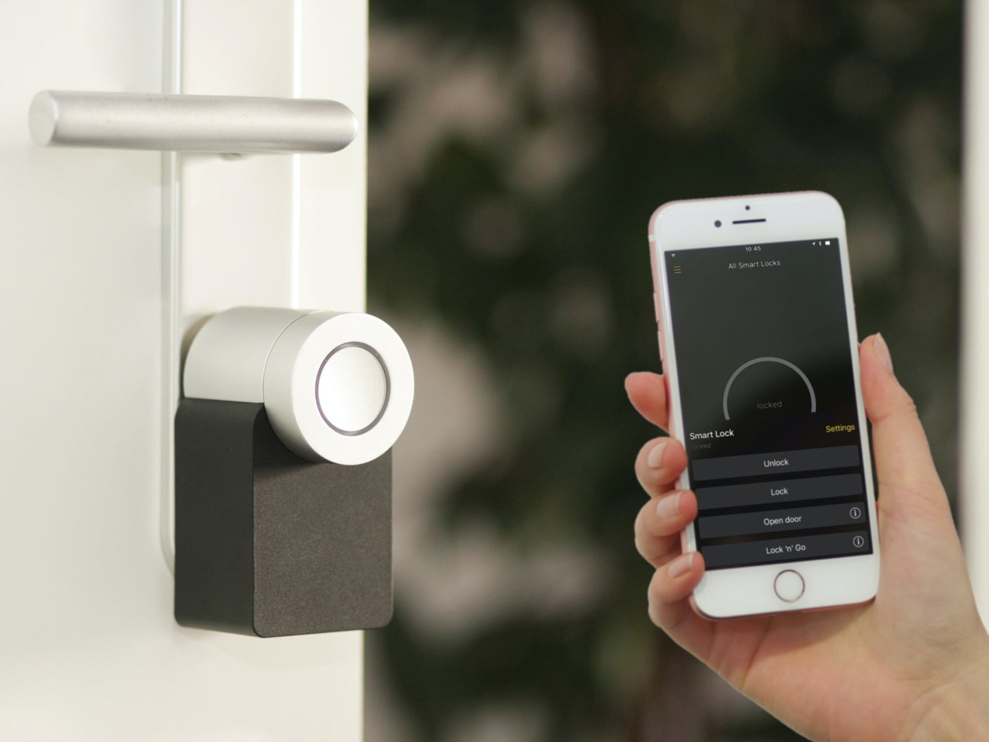 A person holding a smartphone up to a smart lock on a white door.