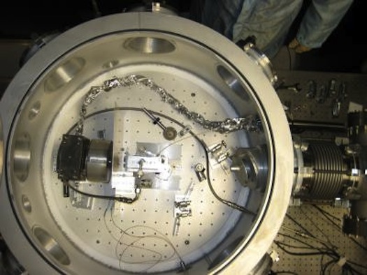 The acceleration, occurring over a distance of about one inch, happens in the interior of the vacuum chamber.