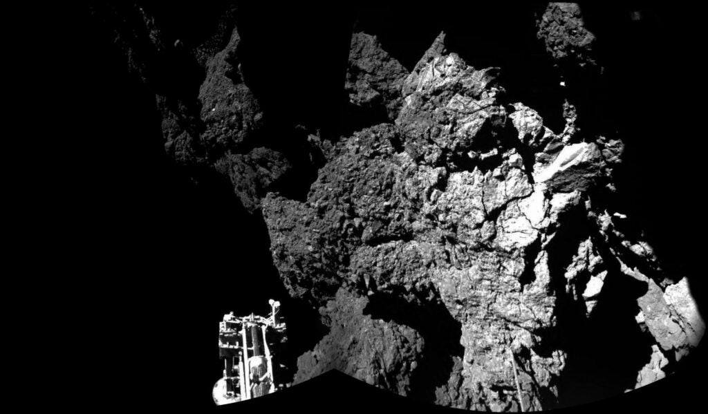 This first-ever image from a comet's surface shows a steep cliff, with one of the lander's feet is in the foreground.