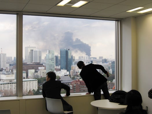 TOKYO, JAPAN - MARCH 11: People look at the smoke rising over the skyline after the earthquake on March 11, 2011 in Tokyo, Japan. A magnitude 8.9 strong earthquake hit the northeast coast of Japan causing Tsunami alerts throughout countries bordering the Pacific Ocean. (Photo by XINHUA/Gamma-Rapho via Getty Images)