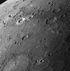 <em>Messenger</em>'s high-resolution images have revealed large areas of Mercury's surface that appear to have been flooded by lava, forming wide expanses of smooth plains. This image shows some of these smooth plains toward the horizon in the upper left corner. A large crater in the lower left has been filled with lava until only portions of its circular rim are visible. Other examples of flooded craters can be spotted throughout the image, along with wrinkle ridges snaking across the plains.