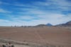 The landscape of the Chajnantor Plateau looks otherworldly, covered with soft red dust and bookended by mountains and volcanoes. The Licancabur volcano, an iconic symbol of the Atacama, is in the background.