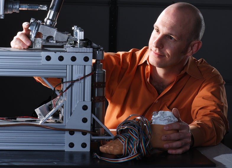 Jerome Rifkin watches his prototype foot flex in a testing rig he built.