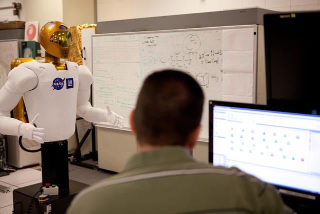 Chris Ihrke, senior project engineer for General Motors, works with Robonaut2 at Johnson Space Center.