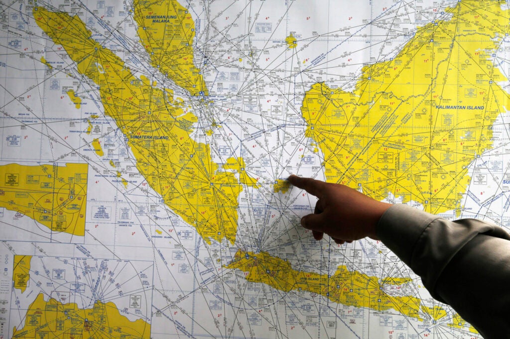 An Indonesian policeman points at a map of Indonesia at a crisis center in Juanda International Airport, Surabaya. The missing AirAsia flight QZ8501 carrying 162 people is presumed to have crashed off the Indonesian coast, an official said on Monday.
