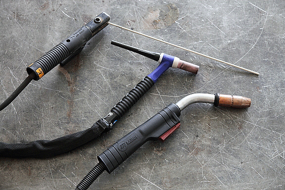 Three welding tools on a concrete floor.