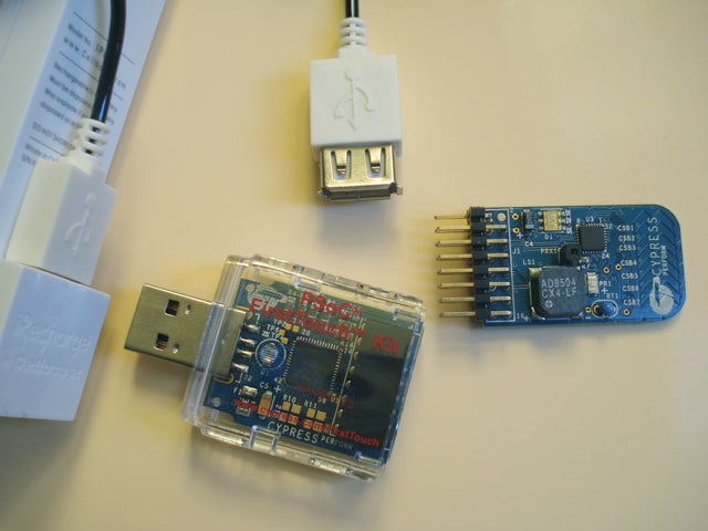 An iPod Shuffle rechargeable battery pack, an FTPC bridge, and an FTMF expansion card on a white surface.