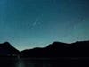 A shooting star appears next to the Milky Way in the sky above Walchensee lake