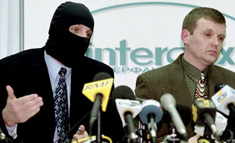 Litvinenko with a masked colleague from the FSB in 1998, accusing the Kremlin of corruption and murder