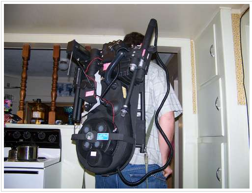 A man wearing a Ghostbusters Proton Pack on his back in a basement.