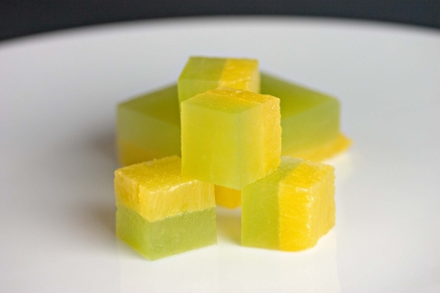 Honeydew and pineapple terrine cubes on a white plate.