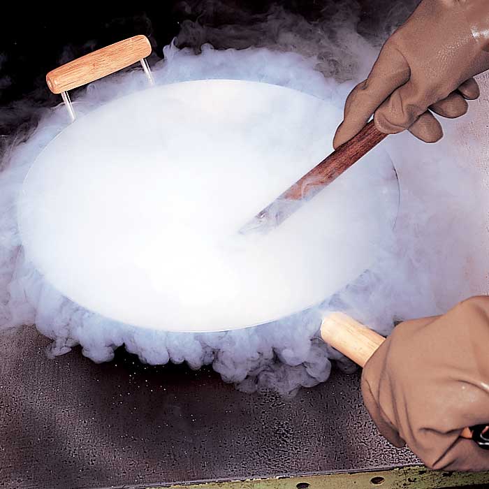 A person stirring a wok full of liquid nitrogen.