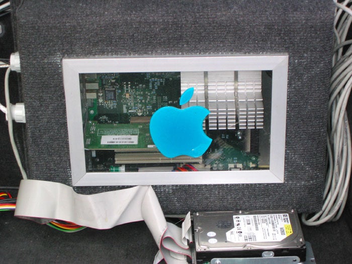 The trunk of a car with a computer motherboard and a Blue Apple logo, with some hard drives.