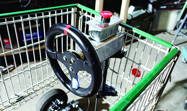 The steering wheel and emergency power off button for a grocery cart go-kart.