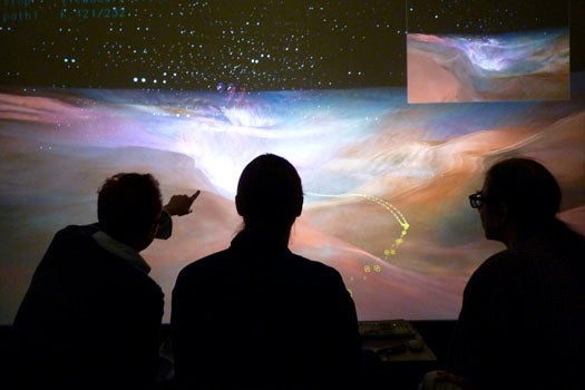 Team members Alex Betts, Robert Patterson and Stuart Levy (left to right) of the Advanced Visualization Lab at NCSA, University of Illinois work in front of an ultra-high resolution 4K 3D display. Wearing circular polarizing glasses, they interactively pre-view a camera flight path to the Orion Nebula during the making of a scene for the Hubble 3D Imax film.