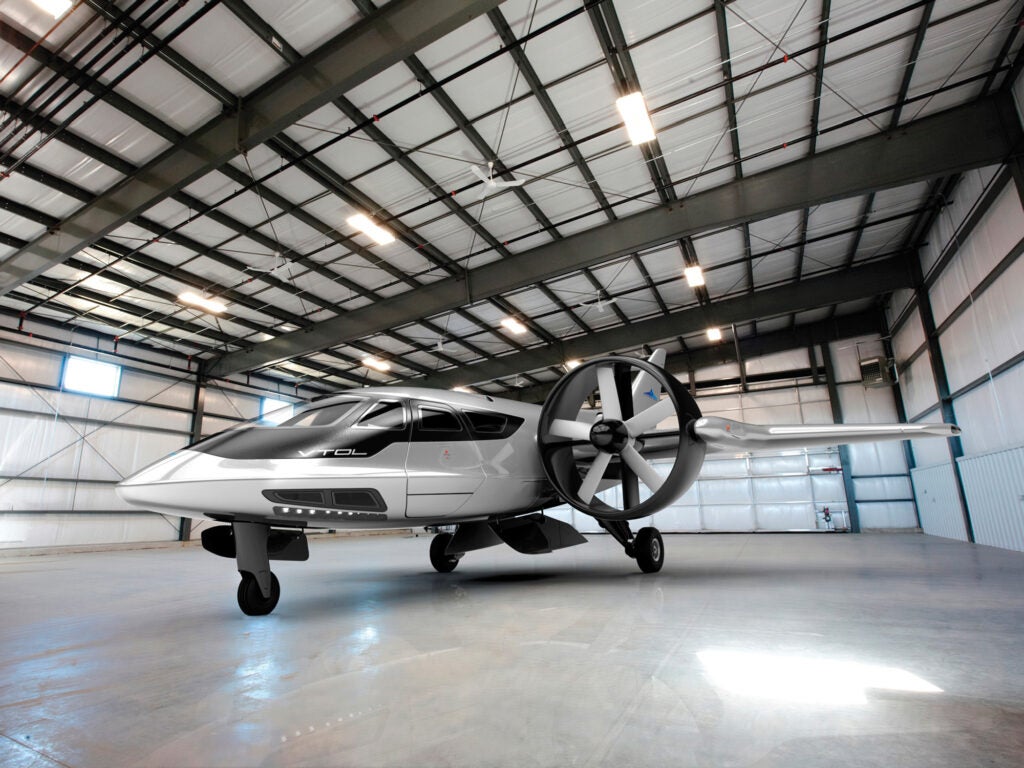 A small white and silver plane in a corrugated-metal hangar