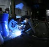 A person welding the frame for a pedal-powered replica tank.