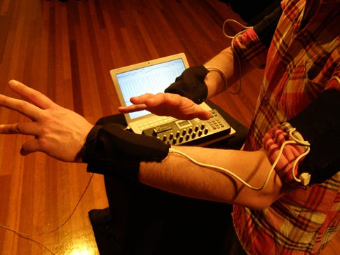 Tom Tlalim with a Wiimote on his wrist and a computer on his lap, gesturing.
