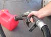 A person filling a red gasoline can from a gas station pump.
