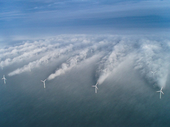 Clouds form in the wake of the front row of wind turbines at the Horns Rev offshore wind farm near Denmark.