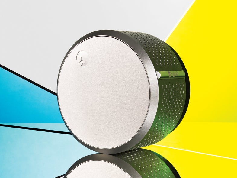 The silver cylinder of the August Smart Lock with yellow and blue in the background