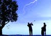 man swinging golf club silhouetted against lightning storm