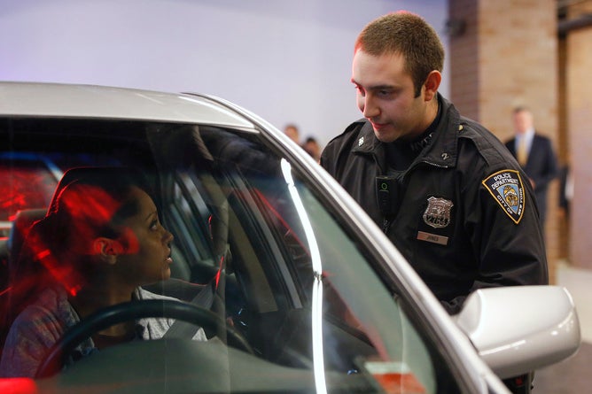 An NYPD officer wearing a body camera speaks with a woman during a traffic stop demonstration of the pilot program involving 60 NYPD officers dubbed 'Big Brother' at the NYPD police academy in the Queens borough of New York, December 3, 2014. REUTERS/Shannon Stapleton (UNITED STATES - Tags: CIVIL UNREST CRIME LAW SCIENCE TECHNOLOGY MEDIA) - RTR4GL9X