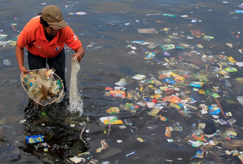 A government sanitary worker collects and segregates garbage, mostly assorted plastic products, polluting Manila bay in the Philippines