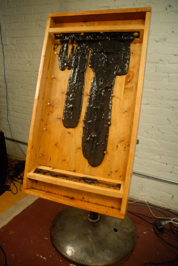 A wooden board with copper nails in it and a large amount of black slime dripping down it.