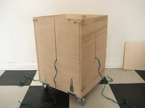 A DIY newspaper baler with twine coming out of its side slits.