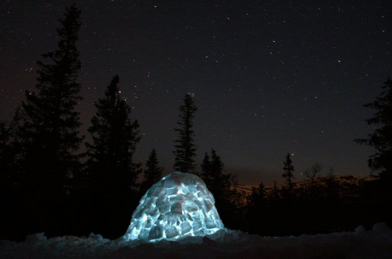 A lit-up igloo under a starry night sky