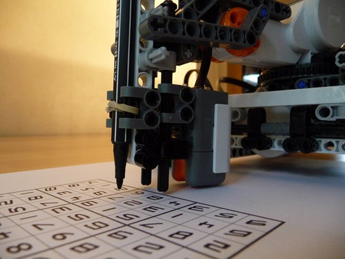 A sudoku-solving robot made out of Legos working on a puzzle.