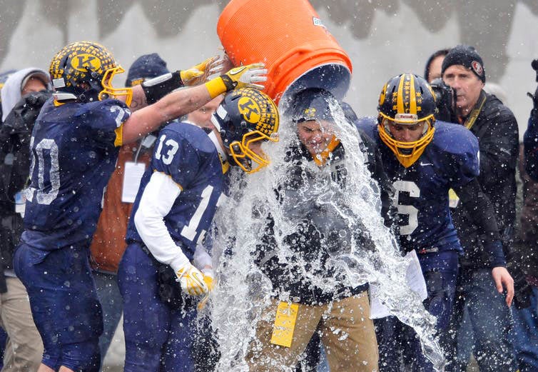football players pouring water on coach